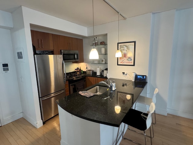 kitchen with kitchen peninsula, stainless steel appliances, decorative light fixtures, a kitchen breakfast bar, and sink