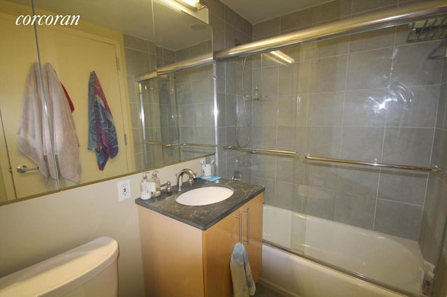 full bathroom with vanity, bath / shower combo with glass door, and toilet