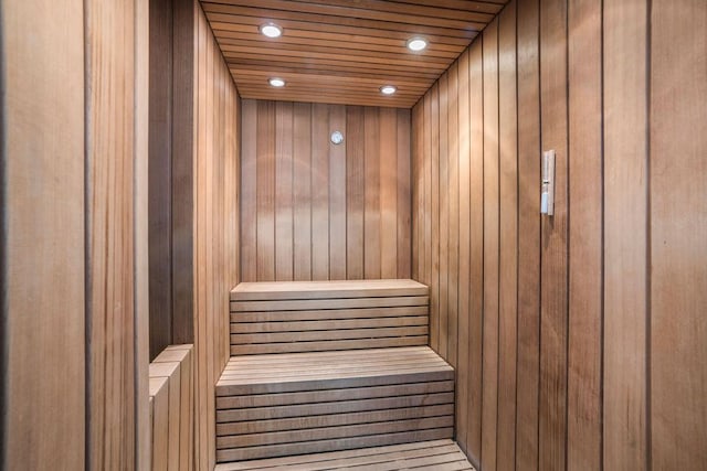 relaxing sauna featuring wooden walls and recessed lighting