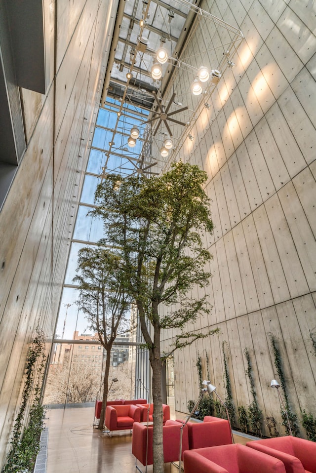 community lobby featuring a towering ceiling, wooden walls, and a wall of windows