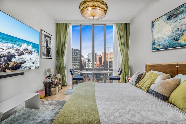 bedroom featuring light wood-type flooring, expansive windows, and a city view