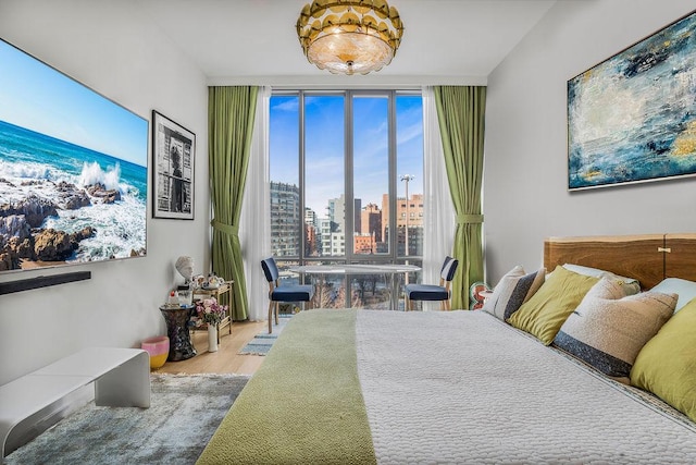 bedroom with a wall of windows, wood finished floors, and a view of skyline