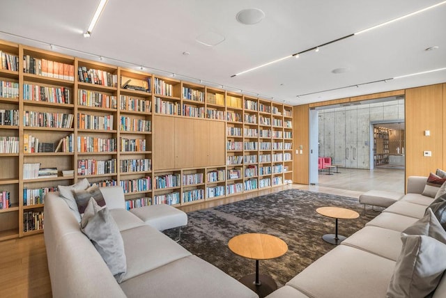 living area with bookshelves, wood walls, and built in shelves