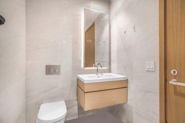 bathroom featuring tile walls, vanity, and toilet