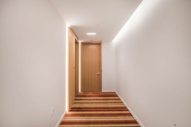 corridor featuring wood finished floors and baseboards