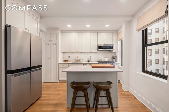 kitchen featuring stainless steel appliances, light hardwood / wood-style floors, and white cabinets