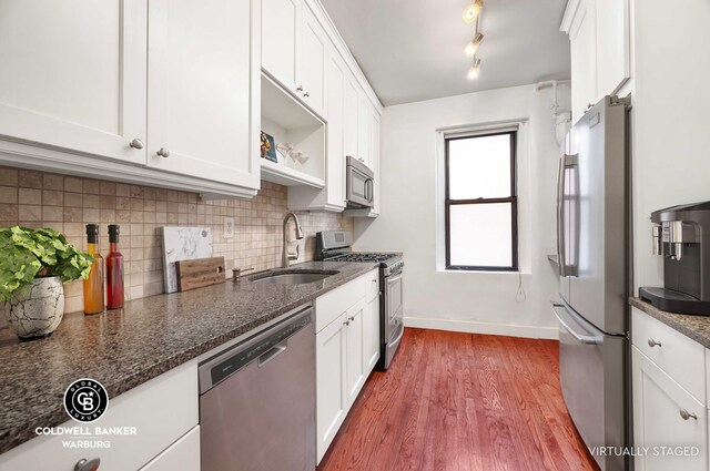 kitchen featuring white cabinetry, appliances with stainless steel finishes, and dark stone countertops