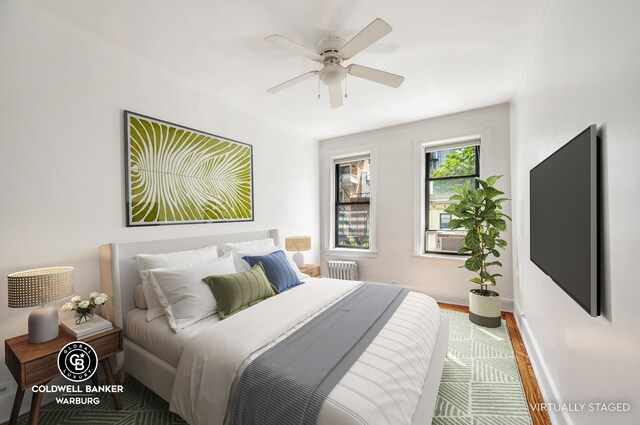 bedroom featuring ceiling fan, wood-type flooring, radiator heating unit, and cooling unit