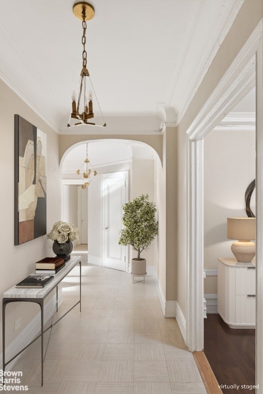 hallway with a notable chandelier and crown molding