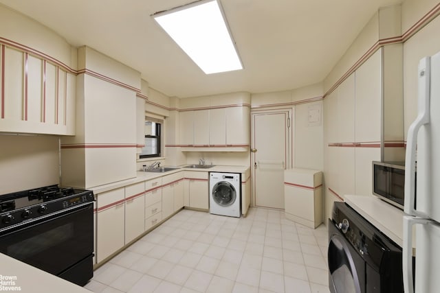 kitchen with light countertops, washer / clothes dryer, stainless steel microwave, and black gas range