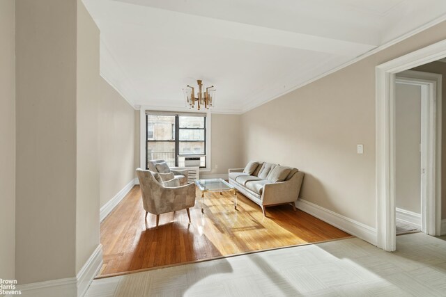 living area with a chandelier, ornamental molding, wood finished floors, and baseboards