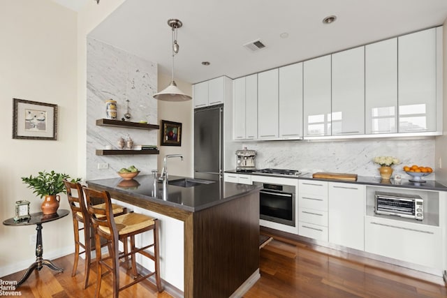 kitchen with sink, white cabinetry, hanging light fixtures, stainless steel appliances, and decorative backsplash