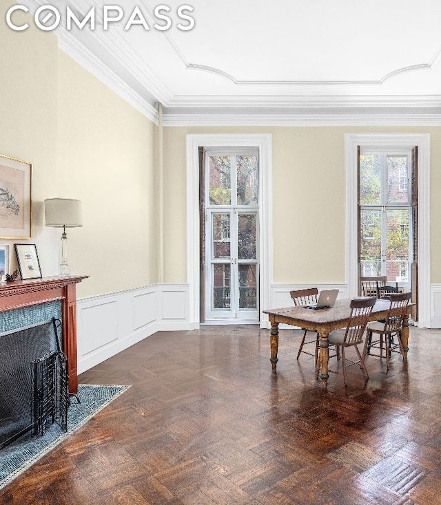 dining area featuring crown molding, a healthy amount of sunlight, and dark parquet flooring