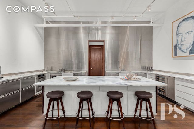 71-73 Bleecker St Unit 2E, New York City, NY 10012 - kitchen with wine cooler, track lighting, light stone countertops, a kitchen island, and a kitchen bar