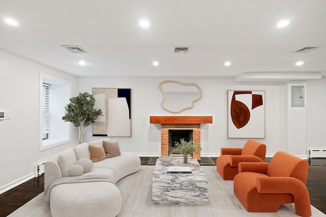 living room with a baseboard radiator, a brick fireplace, and light hardwood / wood-style floors