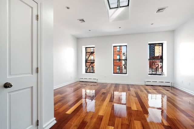 unfurnished room with a baseboard radiator and wood-type flooring