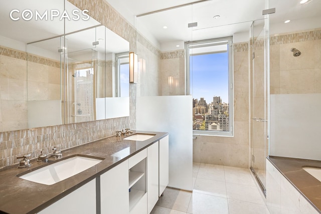 bathroom featuring tile patterned flooring, a sink, tile walls, and a shower stall