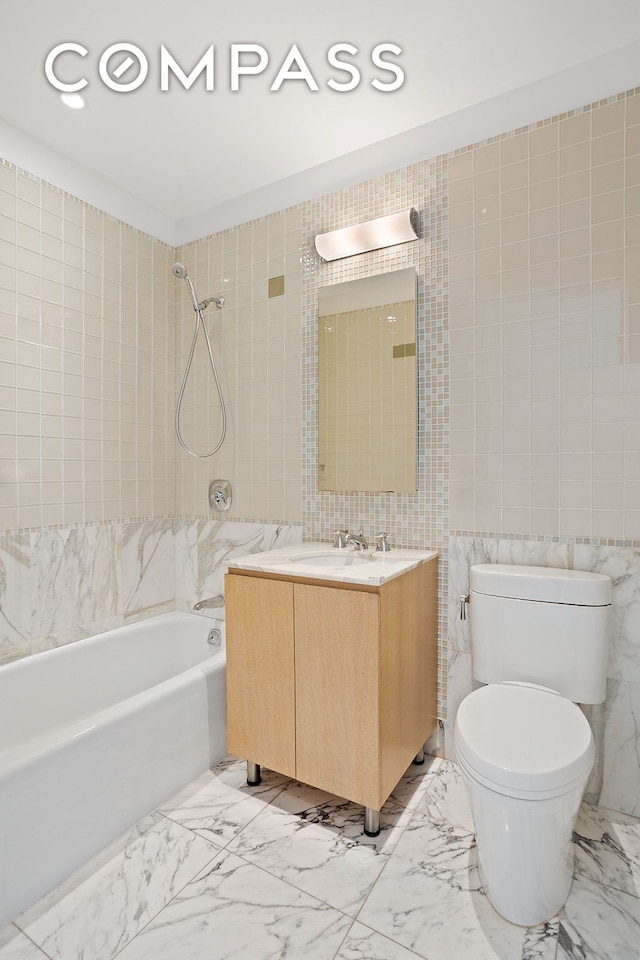 full bath with marble finish floor, tile walls, shower / bath combination, toilet, and vanity