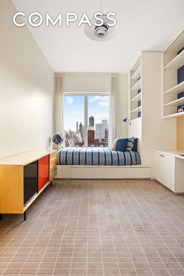 unfurnished bedroom featuring light carpet and a city view