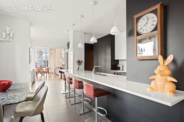 kitchen with a breakfast bar, light countertops, hanging light fixtures, a sink, and modern cabinets