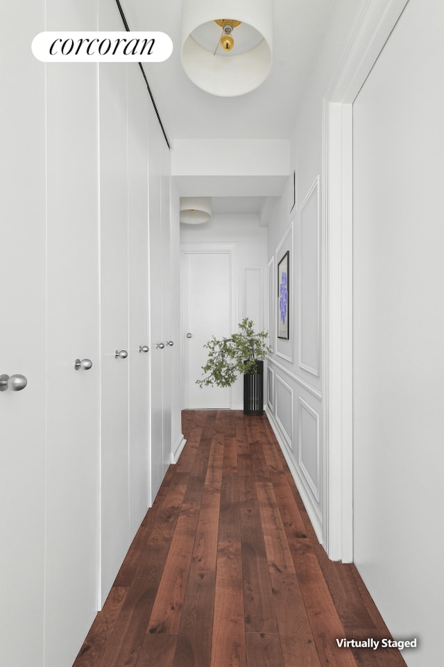 hallway with dark wood finished floors and a decorative wall