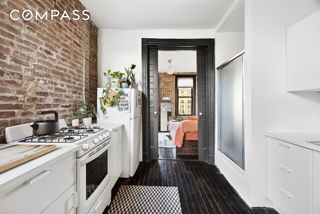 kitchen featuring brick wall, white appliances, and white cabinetry