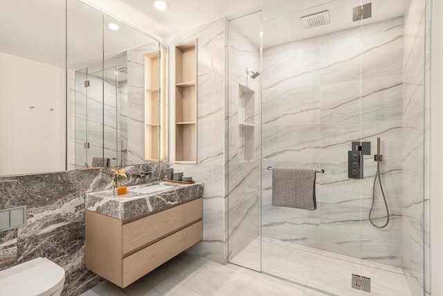 bathroom featuring toilet, tile walls, vanity, and a shower with door