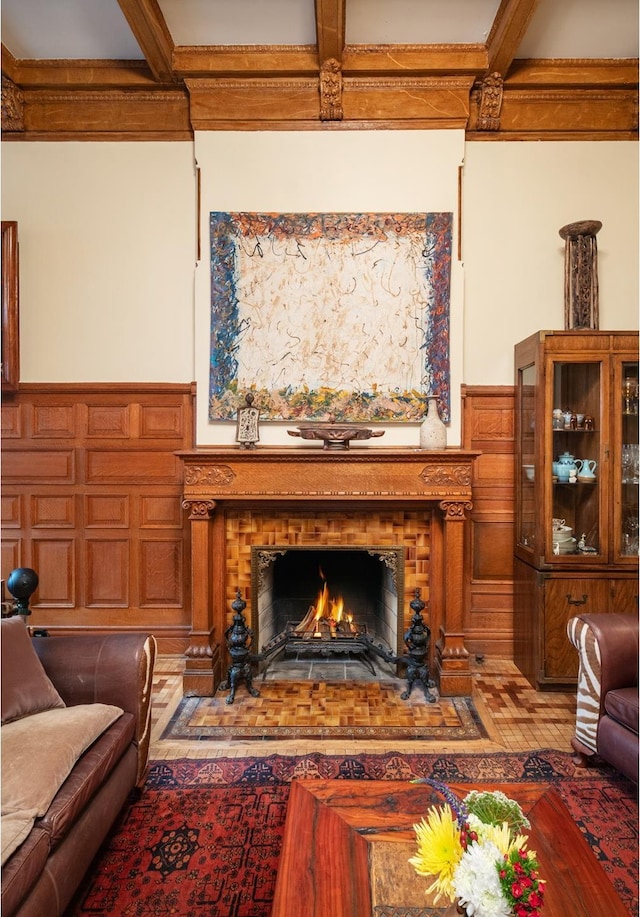 sitting room featuring a wainscoted wall, a fireplace with flush hearth, and beam ceiling