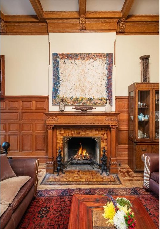 living room with beam ceiling, a tiled fireplace, and coffered ceiling