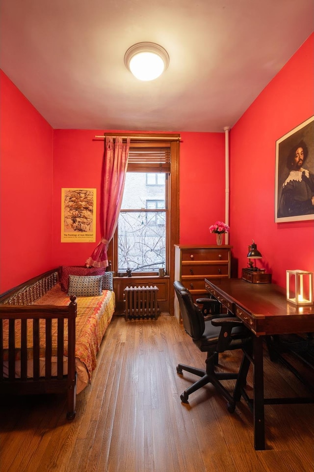 bedroom featuring radiator and hardwood / wood-style flooring