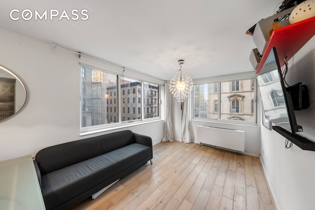 living area featuring radiator, wood finished floors, baseboards, and a chandelier