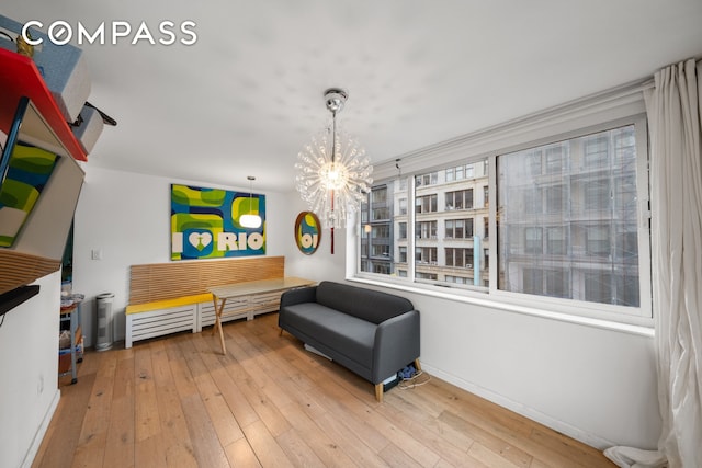 living area featuring baseboards, a chandelier, and hardwood / wood-style flooring