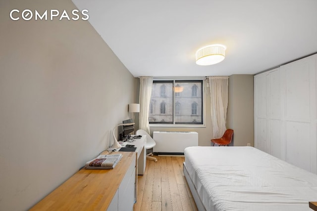 bedroom with radiator heating unit and light hardwood / wood-style flooring