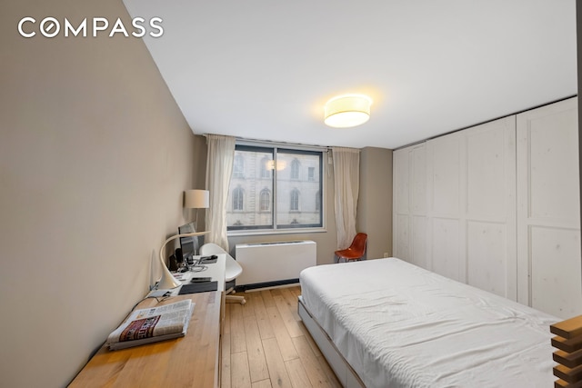 bedroom with light wood-style floors and radiator heating unit