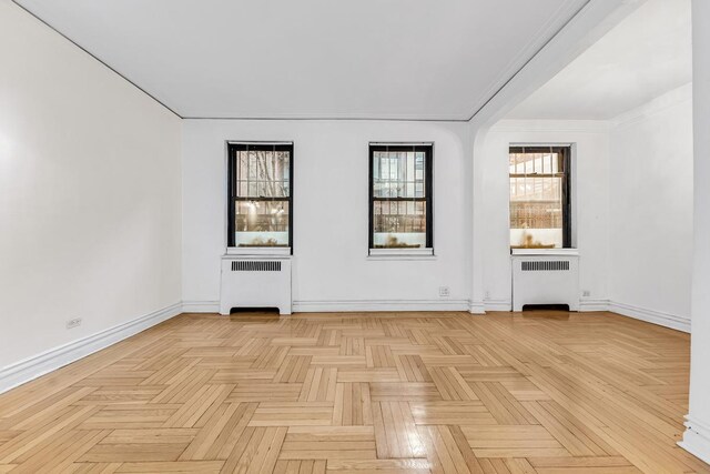 empty room with radiator heating unit and light parquet flooring