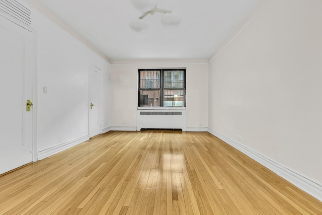 unfurnished room featuring ornamental molding, light wood-type flooring, radiator, and baseboards