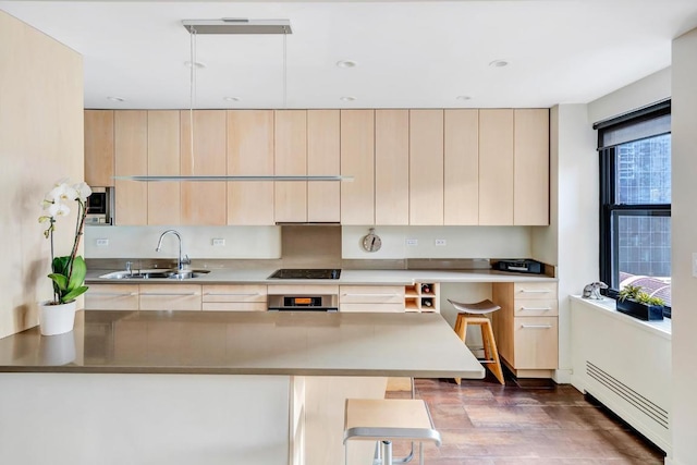 kitchen with kitchen peninsula, appliances with stainless steel finishes, sink, and light brown cabinets