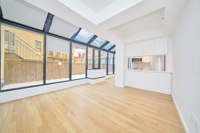 unfurnished living room featuring light hardwood / wood-style flooring and a skylight