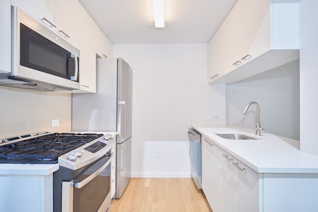 kitchen with a sink, white cabinetry, light countertops, appliances with stainless steel finishes, and tasteful backsplash