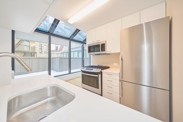 kitchen featuring light countertops, appliances with stainless steel finishes, a sink, and white cabinets