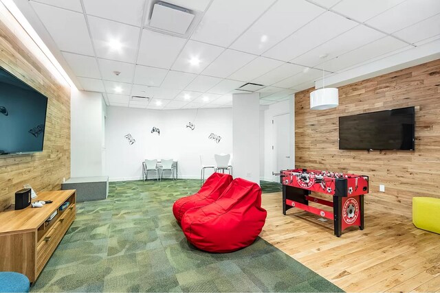 285 W 110th St Unit 2A, New York City, NY 10026 - playroom featuring wooden walls, wood finished floors, a paneled ceiling, and an accent wall