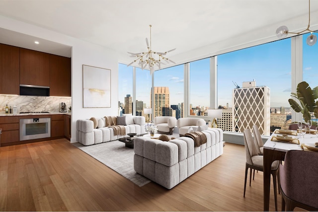 living room featuring a chandelier, a view of city, light wood-style floors, and expansive windows