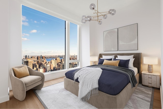 bedroom featuring a view of city, a notable chandelier, and wood finished floors