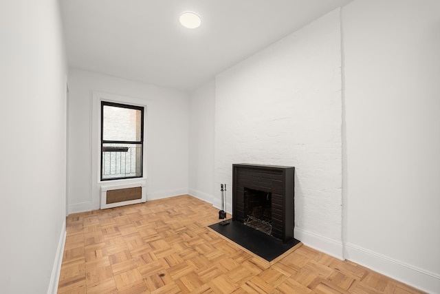 unfurnished living room with a fireplace with raised hearth and baseboards