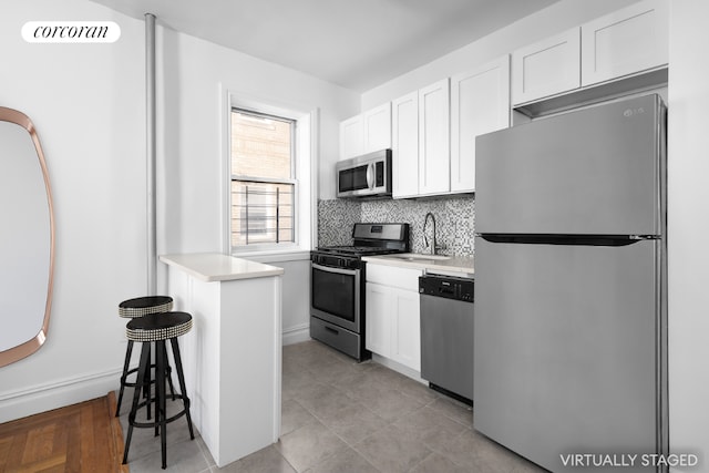 kitchen with light tile patterned floors, white cabinetry, stainless steel appliances, decorative backsplash, and sink