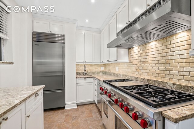 kitchen featuring ventilation hood, high end appliances, white cabinets, and backsplash