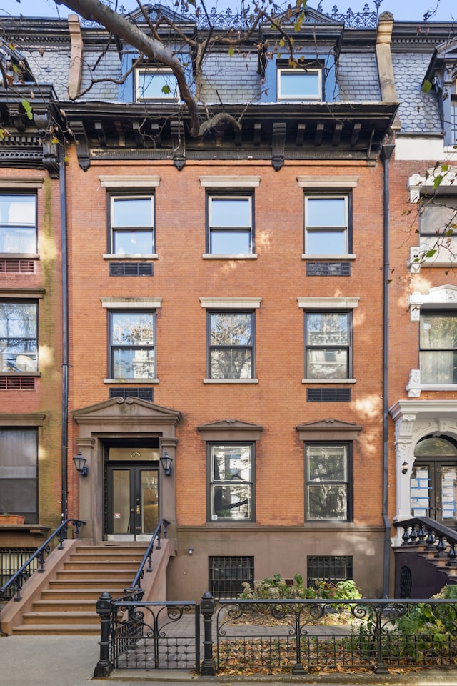 view of front of property with a fenced front yard, mansard roof, and french doors