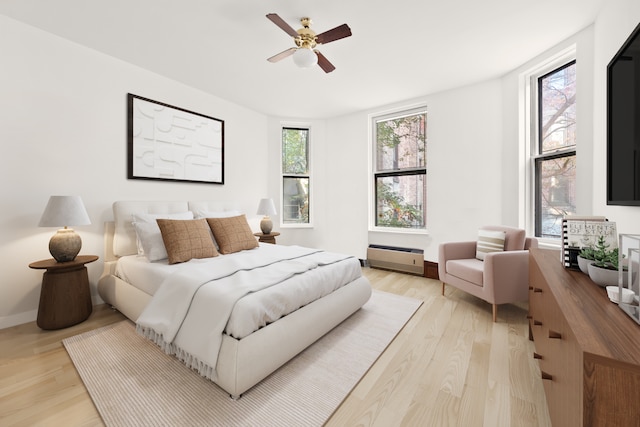 bedroom with light wood finished floors, baseboards, and a ceiling fan