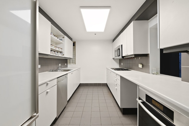 kitchen featuring stainless steel appliances, light countertops, white cabinetry, open shelves, and a sink