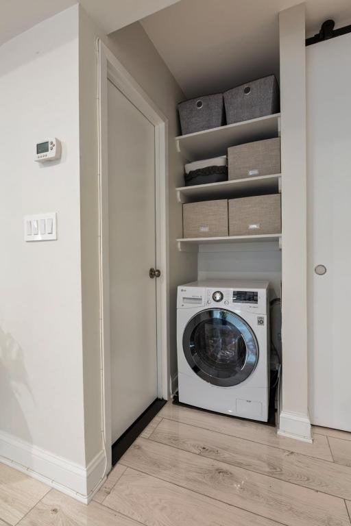 laundry area with washer / clothes dryer and light hardwood / wood-style flooring